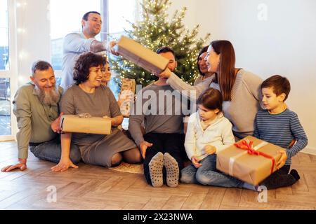 Eine große glückliche Familie schenkt zu Hause unter dem Weihnachtsbaum Geschenke. Eltern, Großeltern, Kinder und Enkel feiern gemeinsam Weihnachten. Lachen Stockfoto