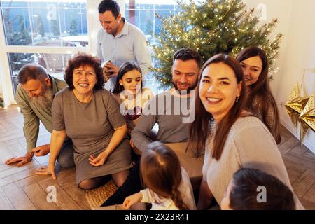 Eine große glückliche Familie schenkt zu Hause unter dem Weihnachtsbaum Geschenke. Eltern, Großeltern, Kinder und Enkel feiern gemeinsam Weihnachten. Lachen Stockfoto