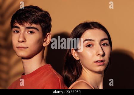 Ein Nahporträt eines lächelnden Mädchens mit Zahnspangen und eines Jungen in sanfter Umarmung. Ein Bruder und eine Schwester mit einem schönen Blattschatten im Gesicht. Ausschneiden Stockfoto