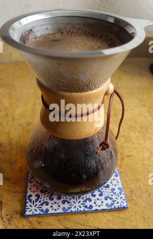 Kaffeemaschine mit Glas auf Keramikfliesen. Vertikaler Shot, komplett, keine Person, gießen Sie die Kaffeemaschine mit frisch gebrühtem Kaffee Stockfoto