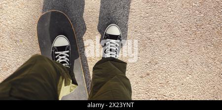 Mann, der auf dem Asphalt der Stadt Skateboard fährt. Skateboarden auf der Straße. POV, Banner mit Kopierbereich Stockfoto