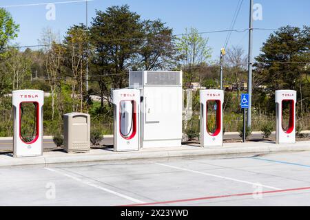 Eine Reihe weißer und roter Tesla-Ladestationen auf einem Parkplatz ohne Fahrzeuge. Stockfoto