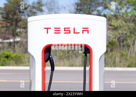 Nahaufnahme einer weiß-roten Tesla-Ladestation auf einem Parkplatz ohne Fahrzeuge. Stockfoto