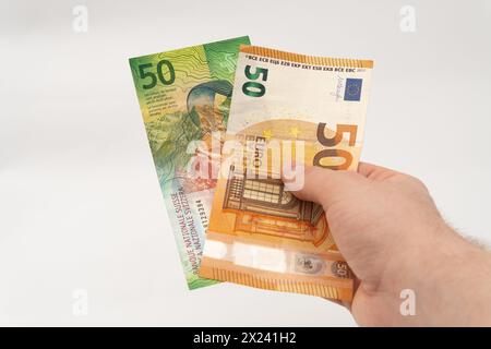 Mann mit 50 CHF Schweizer Franken und 50 Euro Euro Euro Banknotenpapierwährung isoliert auf weißem Hintergrund Stockfoto