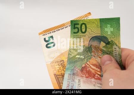 Mann mit 50 CHF Schweizer Franken und 50 Euro Euro Euro Banknotenpapierwährung isoliert auf weißem Hintergrund Stockfoto