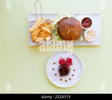 Hamburger mit Pommes frites und Kakaocreme mit Himbeeren Stockfoto