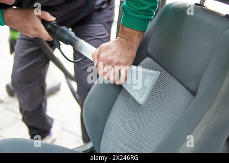 Details zur Fahrzeugreinigung – männlich mit professioneller chemischer Dampfreinigung für schmutzige Innensitze im Auto mit Extraktionsmethode Stockfoto