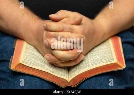 Ein Mann betet Hände an einer offenen Bibel. Stockfoto