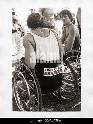 Rollstuhlläufer sprechen nach dem New Yorker Marathon. 1981 im Central Park, NYC. Auf dem Aufkleber steht „I Brake for Runners“ (I Bremse für Läufer). Stockfoto