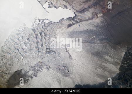 Asien. Februar 2024. Eine Winterlandschaft in Zentralasien wurde von einem Astronauten an Bord der Internationalen Raumstation aufgenommen. Wenn Oberflächen mit Schnee bedeckt sind, sind Texturen nützlicher als Farben für die Interpretation von Landschaften aus der Umlaufbahn. Das strukturlose Gebiet oben links ist die glatte Wasseroberfläche des Bositeng Lake, ein großer See im äußersten Nordwesten Chinas. Die leicht gekrümmte Sandgrube weist darauf hin, dass es sich bei dem eintönigen Gebiet um einen See handelt. Solche Spucke sind häufig in der Nähe von Seeufern zu finden und werden durch Wellen und ländliche Strömungen erzeugt. (Kreditbild: © NASA Earth/ZUMA PR Stockfoto