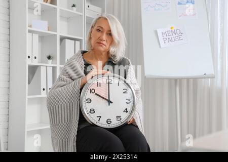 Reife Geschäftsfrau mit Uhr im Büro. Menopause-Konzept Stockfoto