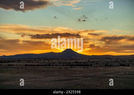 Entfernter Berg bei Sonnenuntergang mit dramatischen orangen Wolken Stockfoto