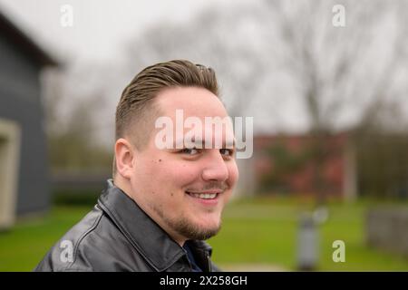 Nahaufnahme eines jungen attraktiven Mannes in seinen Zwanzigern, der im Frühjahr draußen in einem Park stand und freundlich in die Kamera schaute Stockfoto
