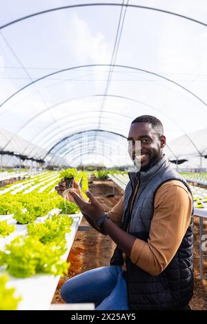 Afroamerikaner junger männlicher Hofaufseher mit Salat, lächelnd im Gewächshaus, Kopierraum Stockfoto