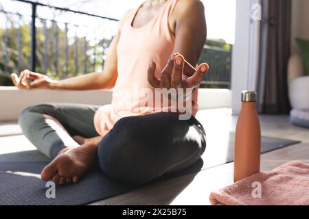 Eine ranghohe Afroamerikanerin, die zu Hause im Kreuz sitzt und Yoga praktiziert Stockfoto