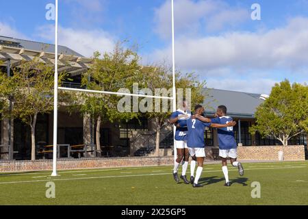 Drei afroamerikanische junge männliche Athleten feiern auf einem Rugbyfeld im Freien Stockfoto
