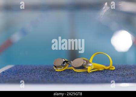 Schwimmbrille am Rand des Pools im Innenbereich, klares Wasser reflektierendes Licht, Kopierraum Stockfoto