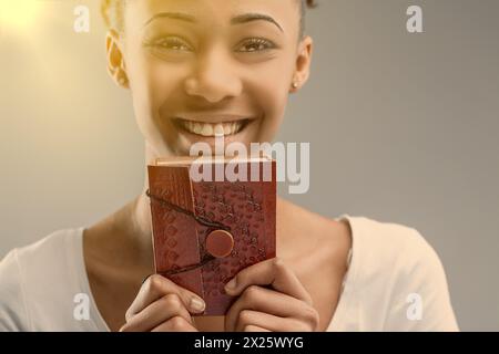 Werfen Sie einen Blick in die seelenvollen Augen einer jungen Frau hinter einem roten, geprägten Lederjournal Stockfoto