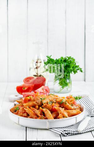 Klassische italienische Pasta Penne Arrabbiata mit Gemüse auf weißem Holztisch. Penne Pasta mit Sauce Arrabbiata. Stockfoto