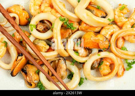 Gebratene Muscheln, Tintenfische und Garnelen und Essstäbchen, Nahaufnahme. Stockfoto