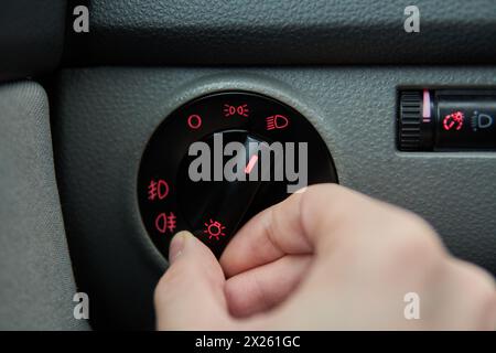 Man Hand schaltet die Bedienungstasten des Scheinwerferschalters ein Stockfoto