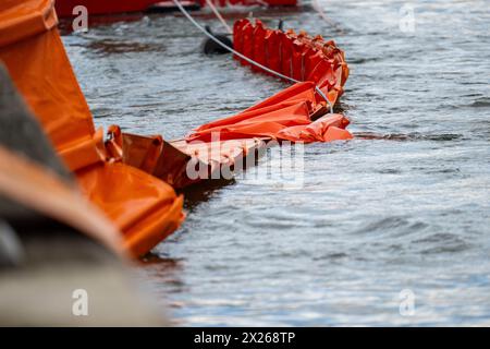 Schweinfurt, Deutschland. April 2024. Eine Ölbarriere wird auf das Wasser gezogen. Die Feuerwehren der Stadt und des Landkreises Schweinfurt und die Wasserrettungseinheiten am Main üben im Katastrophenfall aus. Es wird davon ausgegangen, dass Öl auf fließendes Wasser austritt. Quelle: Pia Bayer/dpa/Alamy Live News Stockfoto