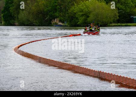 Schweinfurt, Deutschland. April 2024. Eine Ölbarriere wird von einem Feuerwehrboot auf das Wasser gezogen. Die Feuerwehren der Stadt und des Landkreises Schweinfurt und die Wasserrettungseinheiten am Main üben im Katastrophenfall aus. Es wird davon ausgegangen, dass Öl auf fließendes Wasser austritt. Quelle: Pia Bayer/dpa/Alamy Live News Stockfoto