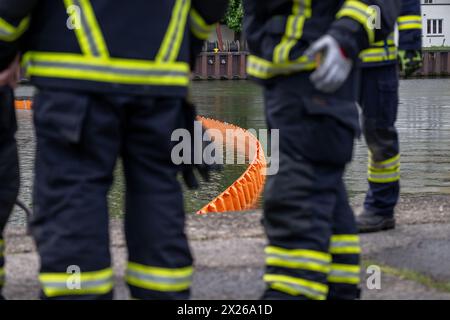 Schweinfurt, Deutschland. April 2024. Ein Ölboom schwimmt auf dem Main, während die Feuerwehr auf der Bank steht. Die Feuerwehr aus Stadt und Bezirk Schweinfurt und Wasserrettungseinheiten am Main üben im Katastrophenfall. Es wird davon ausgegangen, dass Öl auf fließendes Wasser austritt. Quelle: Pia Bayer/dpa/Alamy Live News Stockfoto