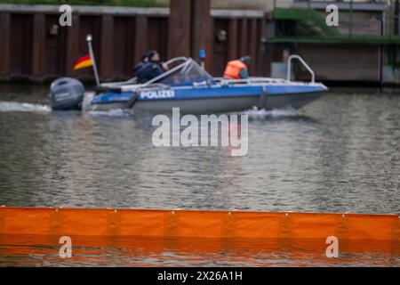 Schweinfurt, Deutschland. April 2024. Eine Ölbarriere überquert den Main, während ein Polizeiboot vorbeifährt. Die Feuerwehr aus Stadt und Bezirk Schweinfurt und die Wasserrettungseinheiten am Main üben eine Katastrophensituation aus. Es wird davon ausgegangen, dass Öl auf fließendes Wasser austritt. Quelle: Pia Bayer/dpa/Alamy Live News Stockfoto