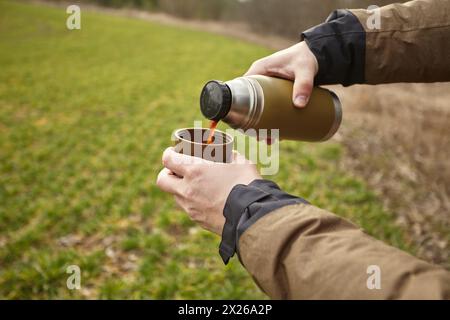 Ein Mann gießt Kaffee aus einer Thermoskanne Stockfoto