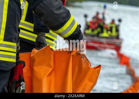 Schweinfurt, Deutschland. April 2024. Eine Ölbarriere wird auf das Wasser gezogen. Die Feuerwehren der Stadt und des Landkreises Schweinfurt und die Wasserrettungseinheiten am Main üben im Katastrophenfall aus. Es wird davon ausgegangen, dass Öl auf fließendes Wasser austritt. Quelle: Pia Bayer/dpa/Alamy Live News Stockfoto