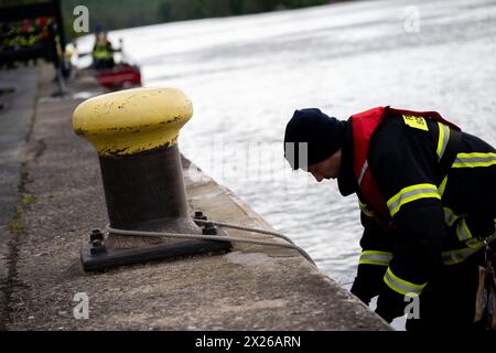 Schweinfurt, Deutschland. April 2024. Ein Feuerwehrmann legt ein Boot an einer Bank an. Die Feuerwehren der Stadt und des Landkreises Schweinfurt und die Wasserrettungseinheiten üben eine Katastrophensituation am Main aus. Es wird davon ausgegangen, dass Öl auf fließendes Wasser austritt. Quelle: Pia Bayer/dpa/Alamy Live News Stockfoto