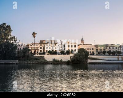 Farbenfrohe Gebäude, darunter Häuser und Geschäfte, blicken auf den Fluss Guadalquivir im Triana-Viertel der Analusischen Stadt Sevilla, Spanien, während der goldenen Zeit Stockfoto