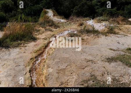 Teil des Netzes von Wasserstraßen, Kanälen und Kanälen im antiken Kurort Bagno Vignoni, Val d’Orcia, Toskana, Italien. Heißes vulkanisches Quellwasser fließt entlang dieses Netzes vom Katharinenbad aus dem 16. Jahrhundert zu den alten Mühlen darunter. Die therapeutische Qualität des Wassers von Bagno Vignoni zieht seit etruskischen Zeiten Besucher in das Dorf. Stockfoto