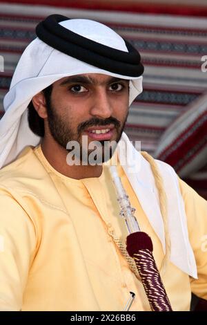 Doha, Katar. Araber aus Abu Dhabi entspannend mit Wasserpfeife im Coffee Shop, mit einer gelben Dishdasha, weißem Kaffiya (Gghutra) und schwarzem Agar (egal). Stockfoto