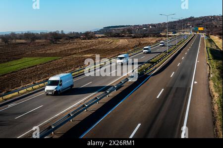 Vier Lieferwagen stehen auf einer Autobahn an. Kleinbus auf einer Straße Stockfoto
