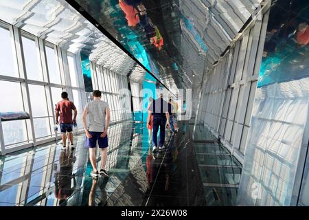 Aussichtsplattform, der Flaschenöffner auf 492 Metern, Menschen, die auf einem Glasboden einer Aussichtsplattform in einem Wolkenkratzer mit Reflexionen laufen, Shanghai Stockfoto
