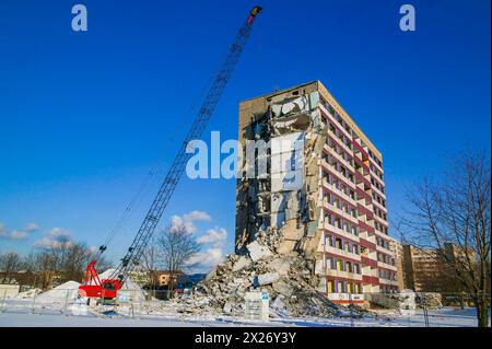 Ein Gebäude wird an einem sonnigen Tag mit schneebedecktem Boden abgebaut Stockfoto