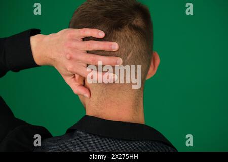 Emotionen eines gutaussehenden Mannes auf grünem Hintergrund, Chromakey-Nahaufnahme, dunkles Haar, junger Mann. Männlicher Erwachsener mit schwarzem Hemd und Hose. Stockfoto