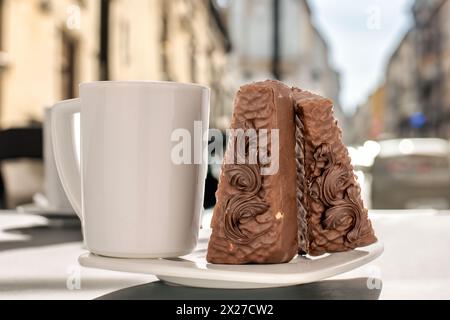 Zwei Stücke Schokoladenwaffelkuchen mit weißer Keramikuntertasse und Tasse auf dem Tisch im Café. Stockfoto