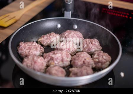 Brausende Fleischbällchen, die in einer Pfanne kochen, mit aufsteigendem Dampf, die die Essenz hausgemachter Komfortgerichte in der Küche einfangen. Hochwertige Fotos Stockfoto
