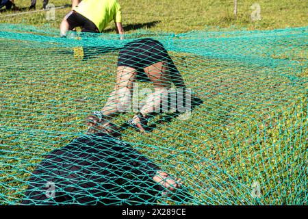 Athleten krabbeln unter einem Netz bei einem Hindernisrennen, einem ocr-Rennen Stockfoto