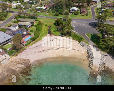 Aus der Vogelperspektive auf eine Bootsrampe entlang eines kleinen Sandstrandes in einer geschützten Küstenbucht an der Mosquito Bay in New South Wales, Australien. Stockfoto