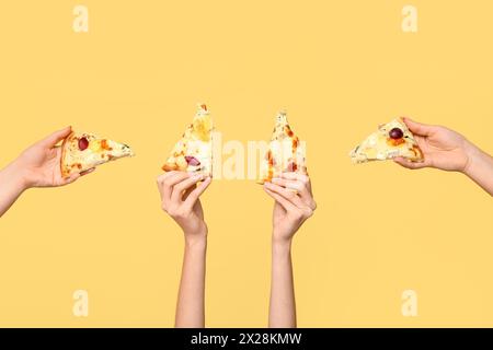 Viele Hände halten Pizzascheiben auf gelbem Hintergrund Stockfoto