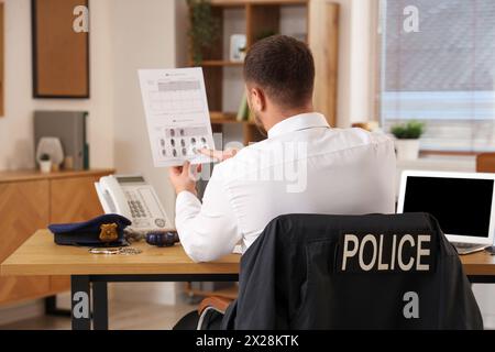 Männlicher Polizist mit Dokument im Büro, Rückansicht Stockfoto