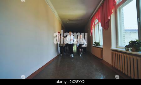 Ein Schuljunge mit einem Down-Syndrom und einer Gruppe von Kindern auf dem Flur, die laufen. Stockfoto