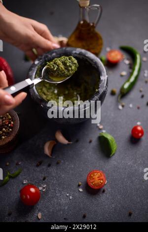 Frau, die grüne Soße in einem Steinmörtel mischt Stockfoto