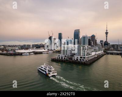 Auckland, Neuseeland - 24. Juli 2023: Aus der Vogelperspektive einer Fähre in Richtung Auckland Downtown Terminal und Geschäftsviertel bei Sonnenuntergang mit ikonischem Sky Stockfoto