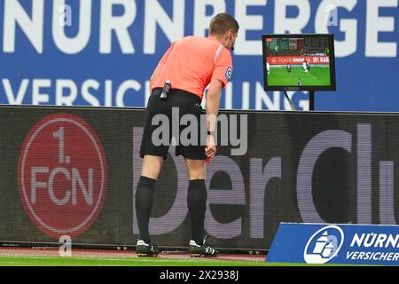 Nürnberg, Deutschland. April 2024. Fußball: Bundesliga 2, 1. FC Nürnberg - SC Paderborn 07, Spieltag 30 im Max Morlock Stadion. Schiedsrichter Florian Exner benutzt Videobeweise, um eine frühere Szene im Strafraum zu überprüfen. Hinweis: Daniel Karmann/dpa – WICHTIGER HINWEIS: gemäß den Vorschriften der DFL Deutscher Fußball-Liga und des DFB Deutscher Fußball-Bundes ist es verboten, im Stadion und/oder des Spiels aufgenommene Fotografien in Form von sequenziellen Bildern und/oder videoähnlichen Fotoserien zu verwenden oder zu nutzen./dpa/Alamy Live News Stockfoto