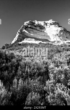 Imposante Sandsteinklippe mit einem kleinen Bogen in schwarz-weiß in den Drakensberg Mountains in Südafrika Stockfoto